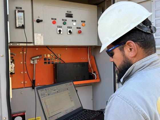 Técnico da Soluxis com notebook no cubículo de proteção